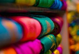 a bunch of colorful t - shirts are stacked on a shelf